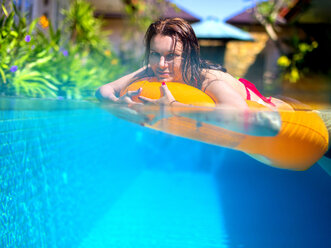 Junge Frau mit schwimmendem Reifen in einem Pool - KNTF000065