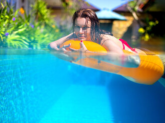 Young woman with floating tire in a pool - KNTF000065