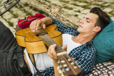 Entspannter junger Mann spielt Gitarre im Freien - UUF004751