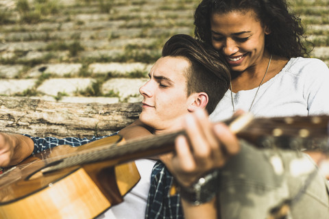 Entspanntes junges Paar mit Gitarre im Freien, lizenzfreies Stockfoto