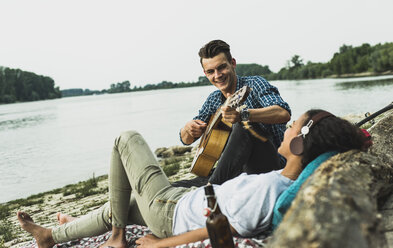 Entspanntes junges Paar mit Gitarre am Flussufer - UUF004756
