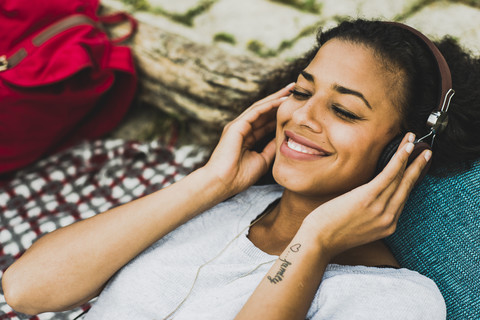 Lächelnde junge Frau mit Kopfhörern im Freien, lizenzfreies Stockfoto