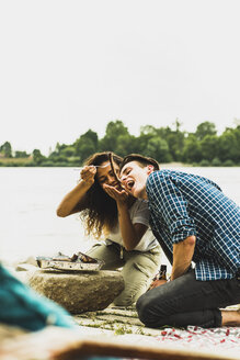 Glückliches junges Paar beim Grillen am Flussufer - UUF004762