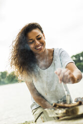 Young woman having a barbecue by the riverside - UUF004763