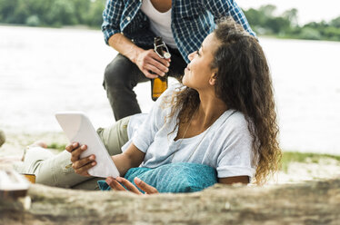 Lächelndes junges Paar mit digitalem Tablet im Freien - UUF004775