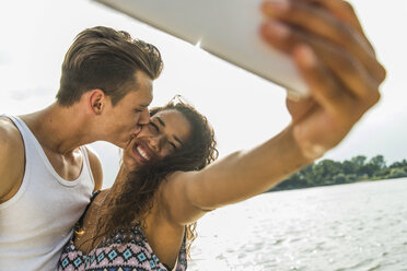 Glückliches junges Paar macht ein Selfie am Flussufer - UUF004798