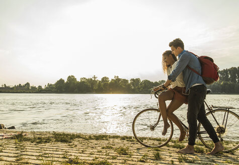 Young couple with bicycle by the riverside - UUF004819