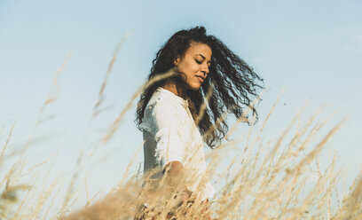 Long-haired young woman in field with tall grass - UUF004823