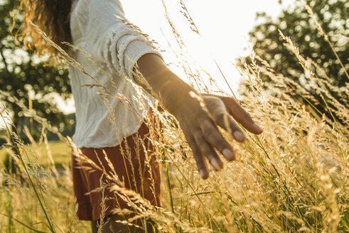 Woman touching tall grass in field - UUF004825