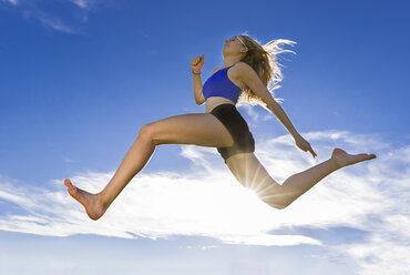 Young athlete jumping under blue sky - STSF000812