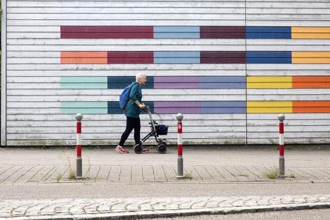 Ältere Frau mit Rollator auf dem Bürgersteig, lizenzfreies Stockfoto