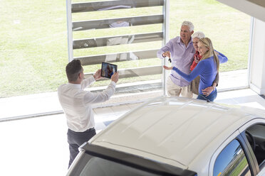 Autohändler beim Fotografieren einer glücklichen Familie mit Autoschlüssel - ZEF006345