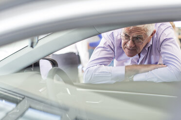 Älterer Mann sieht sich ein neues Auto im Ausstellungsraum an - ZEF006347