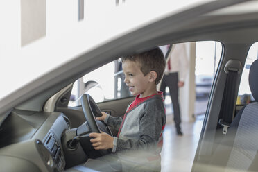 Glücklicher Junge im Autohaus im Inneren der Autolenkung - ZEF006365