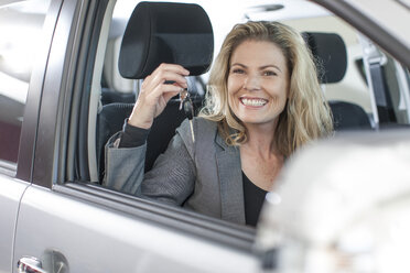 Portrait of smiling woman holding key in new car - ZEF006376