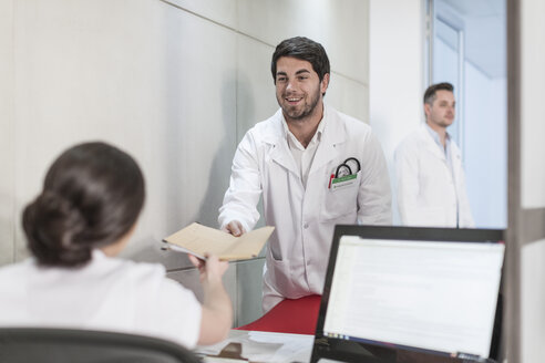 Nurse and doctor with folder at clinic reception - ZEF005925