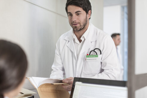 Nurse and doctor with folder at clinic reception - ZEF005926