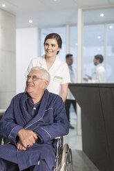 Krankenschwester mit Patient im Rollstuhl am Empfang der Klinik - ZEF005931