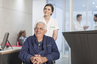 Krankenschwester mit Patient im Rollstuhl am Empfang der Klinik - ZEF005932