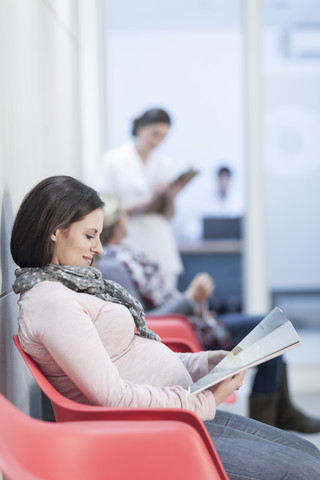 Schwangere Frau im Wartebereich einer Klinik, lizenzfreies Stockfoto