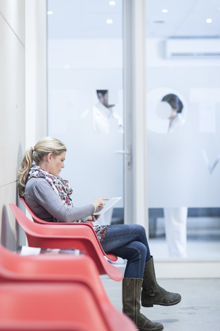 Frau mit digitalem Tablet im Wartebereich einer Klinik, lizenzfreies Stockfoto