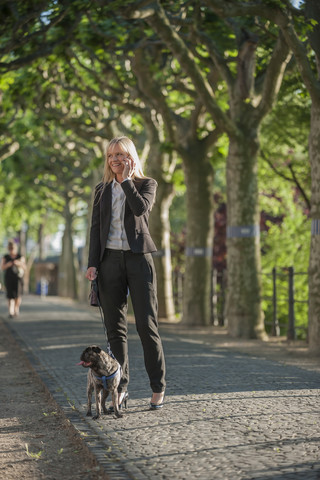 Lächelnde Geschäftsfrau beim Telefonieren mit ihrem Smartphone, lizenzfreies Stockfoto