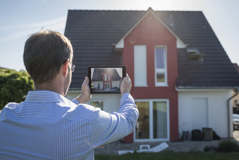 Man photographing his house with digital tablet - PAF001433