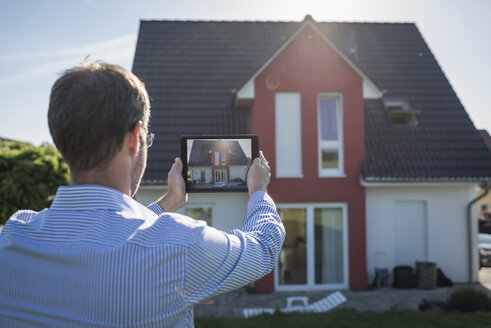 Mann fotografiert sein Haus mit digitalem Tablet - PAF001433