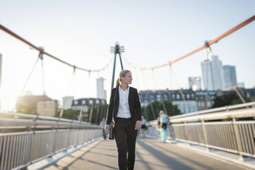 Businesswoman walking on a bridge at twilight - PAF001445