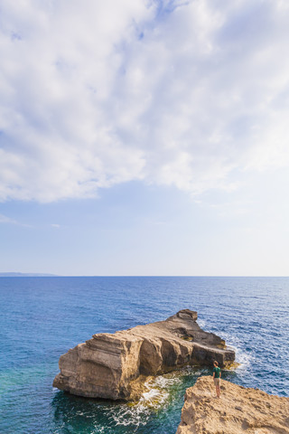 Griechenland, Ägäische Inseln, Rhodos, junger Mann auf der Suche nach einer felsigen Insel, lizenzfreies Stockfoto