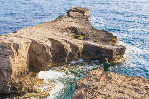 Greece, Aegean Islands, Rhodes, young man standing on rocky island - WDF003136