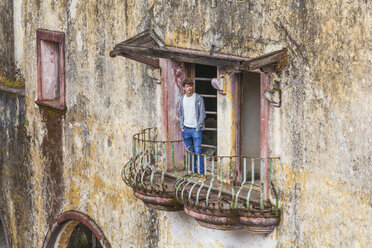 Griechenland, Rhodos, Eleousa, junger Mann steht auf Balkon eines alten Hauses, Ruine aus italienischer Besatzungszeit - WDF003140