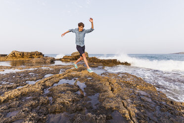 Griechenland, Rhodos, junger Mann springt auf Felsen an der Strandpromenade - WDF003143