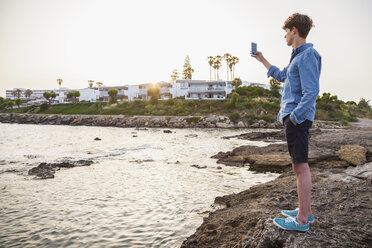 Griechenland, Rhodos, junger Mann fotografiert mit Smartphone an der Strandpromenade - WDF003147