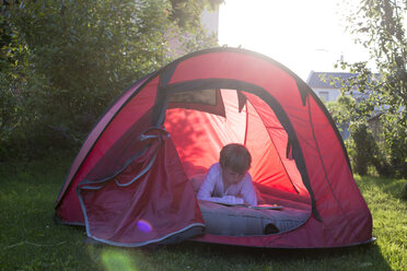 Lesender Junge in einem roten Zelt in der Abenddämmerung - SARF001929