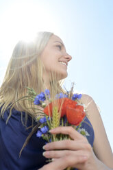 Smiling young woman with bunch of field flowers - BFRF001226