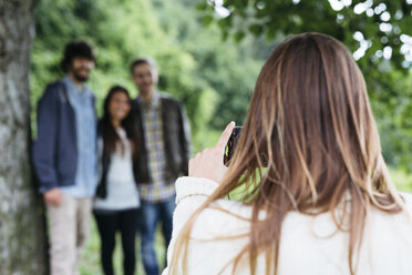 Young woman taking a picture of her three friends with a camera - GIOF000017