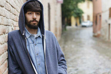 Italy, San Gimignano, portrait of pensive young man wearing hooded jacket - GIOF000027