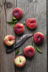 Doughnut peaches and old rusty knife on wood - CSF025742