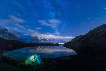 France, Mont Blanc, Lake Cheserys, lit tent on the shore of the lake by night with Milky way and Mount Blanc reflected in the lake - LOMF000004