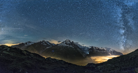 France, Mont Blanc, Lake Cheserys, Milky way and Mount Blanc by night with the valley lighted by the lights of the town of Chamonix stock photo