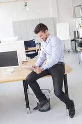 Smiling businessman using digital tablet in an office - JUNF000330