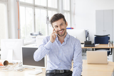 Porträt eines lächelnden Geschäftsmannes beim Telefonieren in einem Büro - JUNF000324