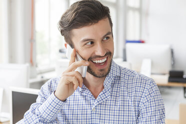 Porträt eines lächelnden Geschäftsmannes beim Telefonieren in einem Büro - JUNF000325