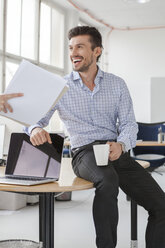 Porträt eines lächelnden Geschäftsmannes mit Kaffeetasse in einem Büro - JUNF000327