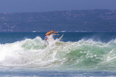 Indonesien, Bali, Mann surft auf einer Welle - KNTF000131
