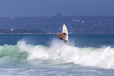 Indonesien, Bali, Mann surft auf einer Welle - KNTF000132