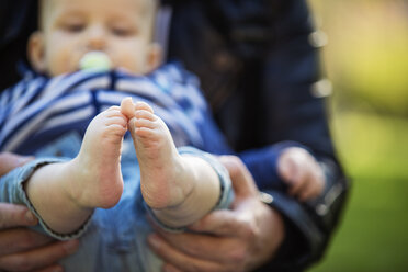 Feet of baby boy holding by his father - TAM000149