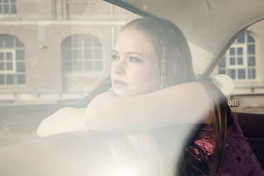 Young woman looking through window of vintage car - TAM000205