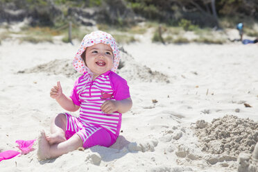 Spain, Majorca, smiling baby girl sitting on the beach - ROMF000062